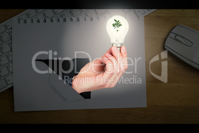 Composite image of hand holding environmental light bulb