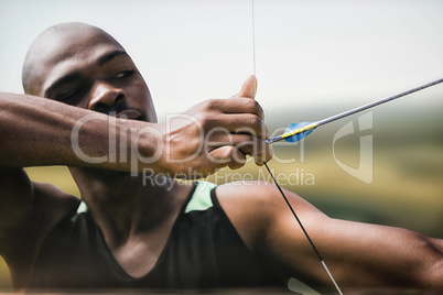 Composite image of close up of man stretching his bow