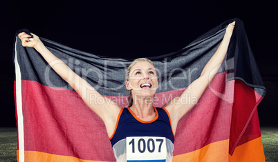 Composite image of athlete posing with german flag after victory