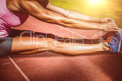 Composite image of close up of sportswoman stretching her muscle