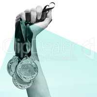 Composite image of hand holding three medals on white background