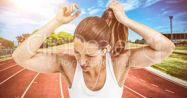 Composite image of athlete woman tying her hair and listening to