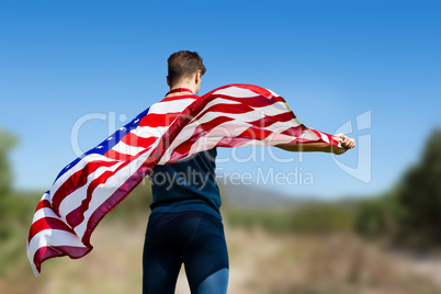 Composite image of rear view of sportsman holding an american fl