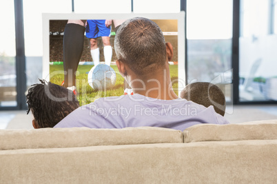 Composite image of two children sitting on sofa with their fathe