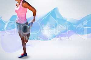Composite image of sporty woman stretching her leg