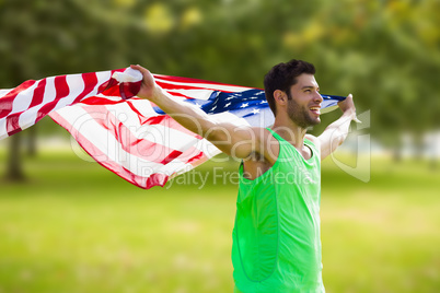 Composite image of happy sportsman holding a american flag