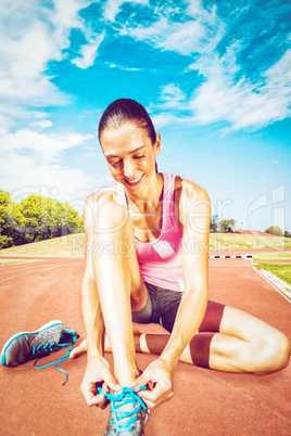 Composite image of a sporty woman doing her shoelace