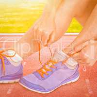 Composite image of athlete woman tying her running shoes