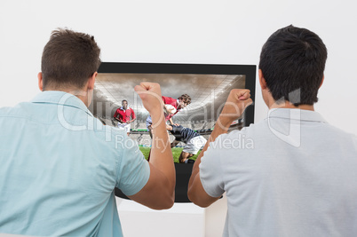 Composite image of two excited soccer fans watching tv