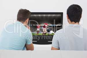 Composite image of two soccer fans watching tv