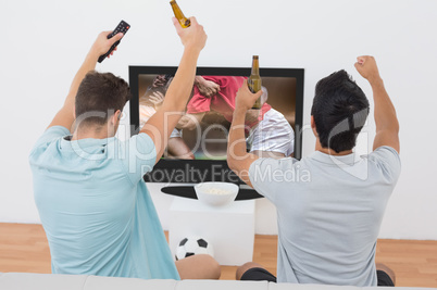 Composite image of excited soccer fans watching tv