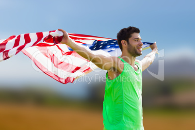 Composite image of happy sportsman holding a american flag