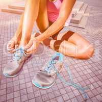 Composite image of athletic woman lacing up shoes