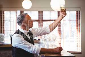 Bartender holding up a wine glass at bar counter