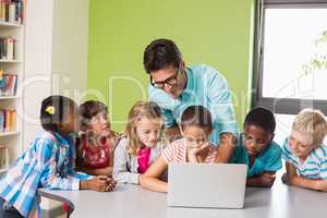 Teacher and kids using laptop in library