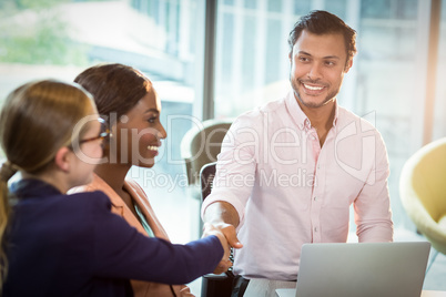 Coworker shaking hands with a colleague during meeting