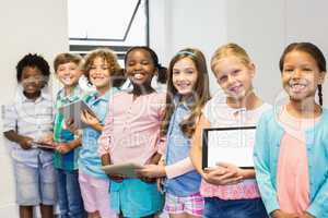 Portrait of students holding digital tablet in classroom