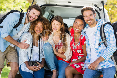 Group of friends on trip sitting in trunk of car