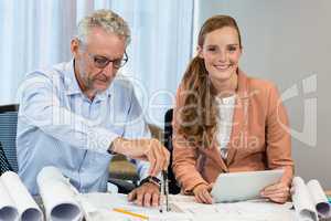 Businesswoman holding digital tablet while coworker working on b
