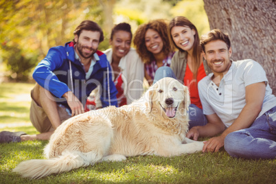 Group of happy friends sitting together with the dog