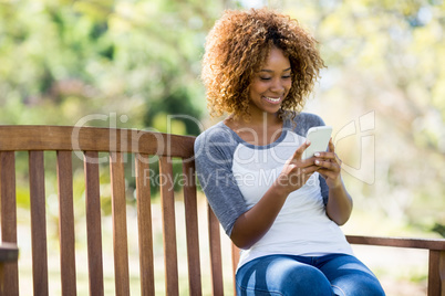 Woman using mobile phone while sitting on the bench