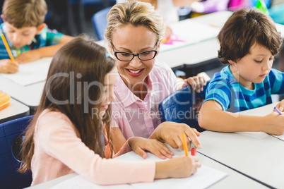 Teacher helping girl with their homework in classroom