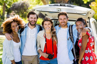 Portrait of happy friends standing with arm around in park