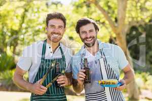 Portrait of two happy men holding barbecue meal and beer bottle