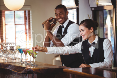 Female bartender garnishing cocktail with olive