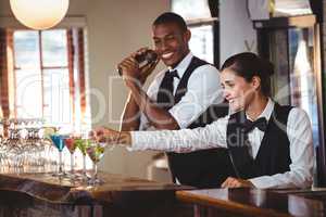 Female bartender garnishing cocktail with olive