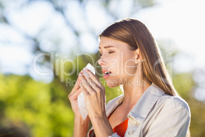 Beautiful woman using tissue while sneezing