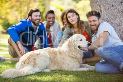 Group of happy friends sitting together with the dog