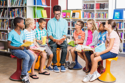 Teacher and kids reading book in library