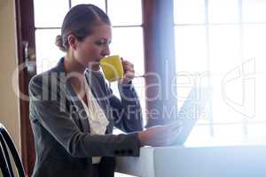 Woman drinking coffee and using tablet