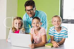 Teacher and kids using laptop in library