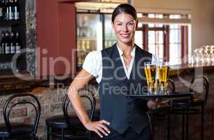 Portrait of waitress holding serving tray with two glass of beer