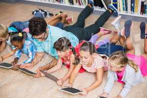 Teacher and kids using digital tablet in library