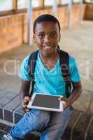 Schoolboy sitting on staircase using digital tablet
