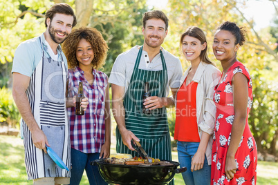 Portrait of happy friends preparing a barbecue grill in park