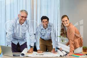 Businesswoman and coworker with blueprint on the desk