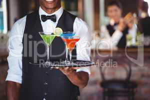 Bartender holding serving tray with cocktail glasses