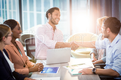 Coworker shaking hands with a colleague during a meeting