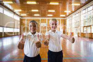 Smiling boys showing thumbs up in school gym