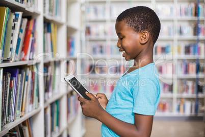 Schoolboy using digital tablet in library