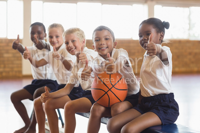 Smiling students with basketball showing thumbs up