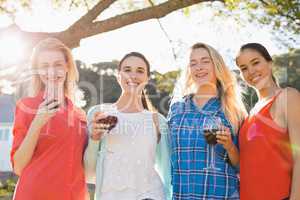 Beautiful women holding a glasses of red wine in park