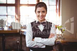 Smiling female bartender standing with arms crossed