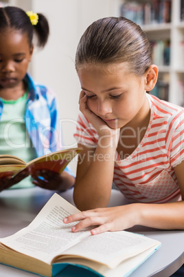 Schoolgirl reading a book in library