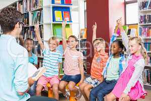 Kids raising their hands in library