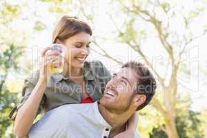 Man giving piggyback to woman while having glass of beer